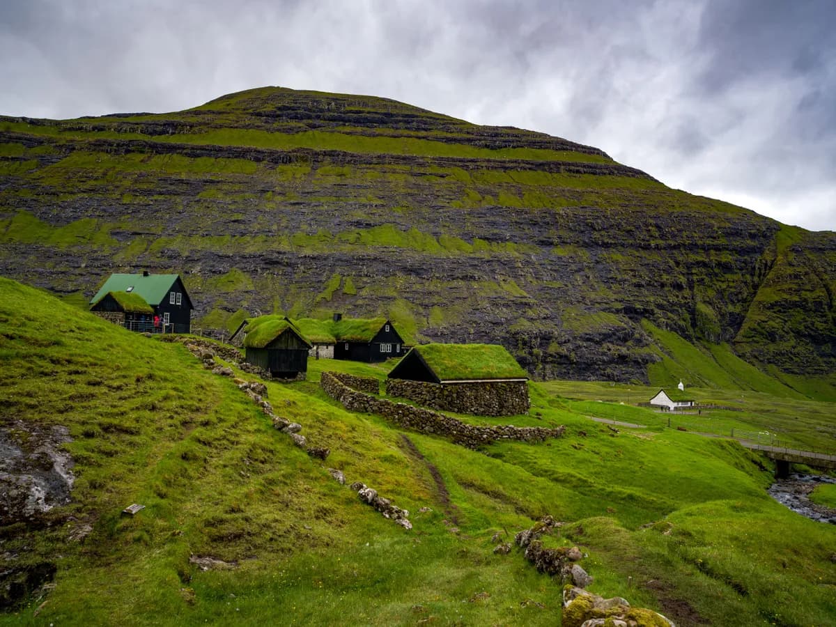 BookNoFees Imagem de exemplo: casas com telhados cobertos de grama em uma paisagem nas Ilhas Faroé