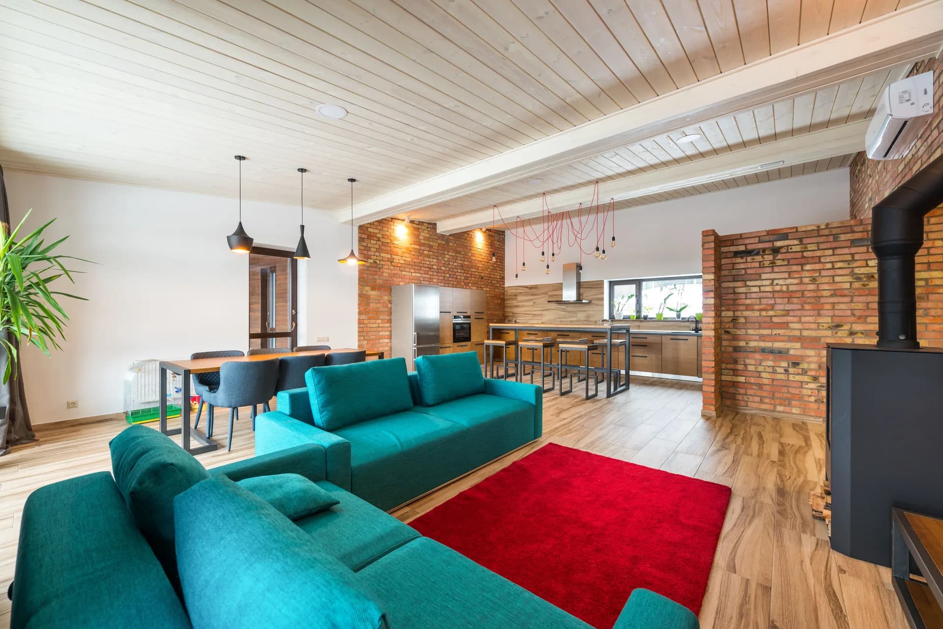 BookNoFees Imagem de exemplo: sala de estar aberta com sofá turquesa, parede de tijolos e cozinha