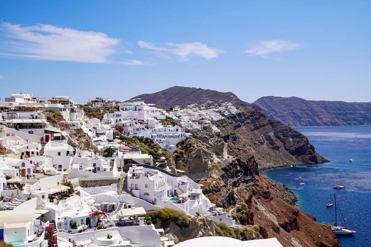 BookNoFees Imagem de exemplo: Casas brancas à beira-mar em uma encosta íngreme das Cíclades