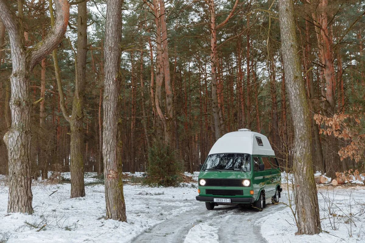 BookNoFees Imagem de exemplo: van de camping verde com teto alto em uma floresta coberta de neve