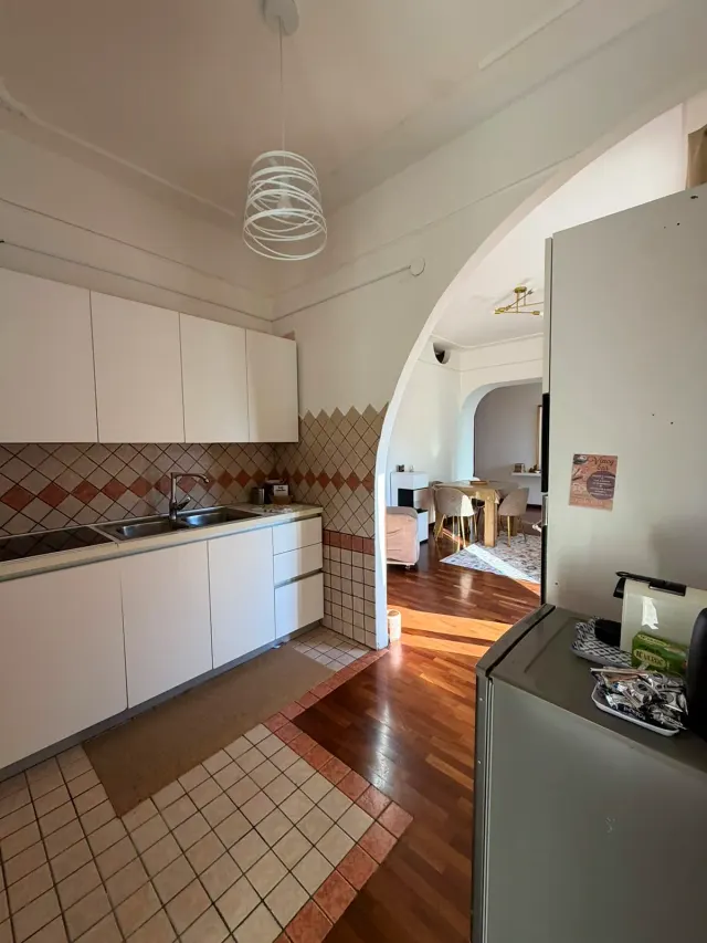 BookNoFees: aluguel de temporada em Castellammare Di Stabia, A campanha, Itália – Cozinha com armários brancos, azulejos na parede atrás da pia e porta em arco que dá acesso à área de jantar