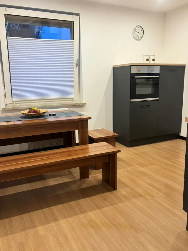 BookNoFees: aluguel de temporada em Bodenwerder – Cozinha com mesa de jantar de madeira, banco, fogão embutido e janela com persiana
