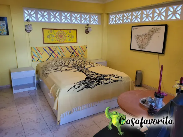 BookNoFees: aluguel de temporada em Buen Paso, Tenerife, Espanha – Quarto com cama de casal, colcha com estampa de árvores e janelas decorativas de blocos de concreto
