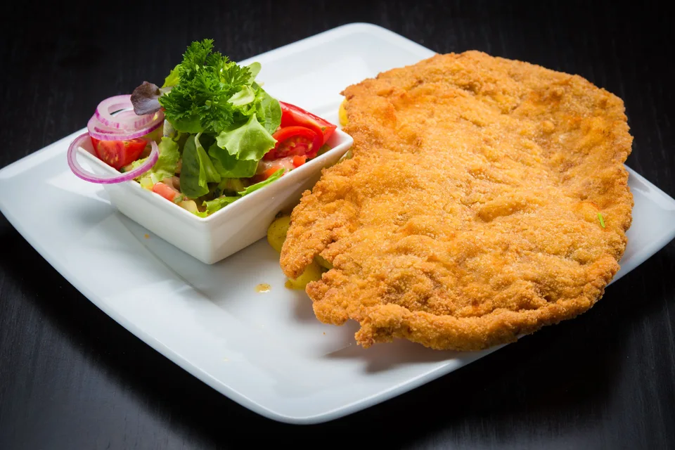 BookNoFees: Fotografia ilustrativa: Escalope panado com salada de acompanhamento num prato branco