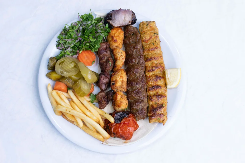 BookNoFees: Fotografia ilustrativa: Espetadas grelhadas servidas com salada e batatas fritas