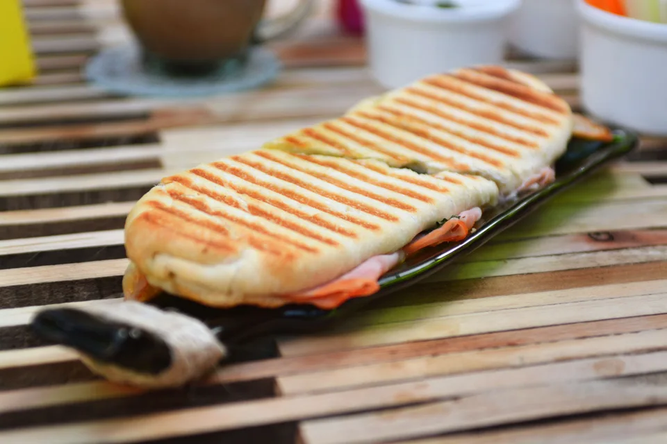 BookNoFees: Fotografia ilustrativa: Panini tostado com marcas da grelha num prato escuro