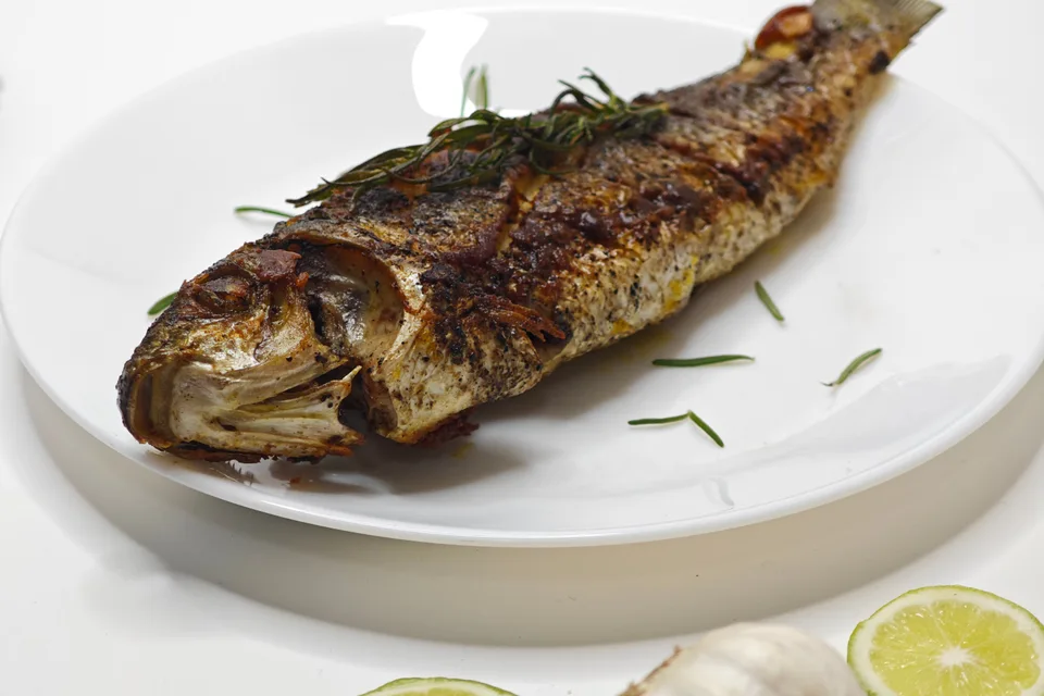 BookNoFees: Fotografia ilustrativa: Peixe inteiro grelhado num prato branco